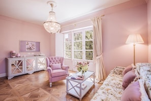 A pink-themed living room with a chandelier, a sofa, a chair, a coffee table, and a cabinet. - Executive Suite with Terrace in Sorrento Center (Sorrento)