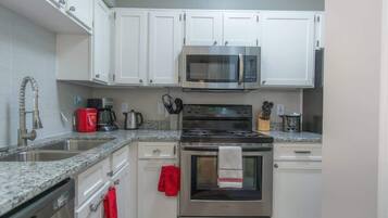 A kitchen with white cabinets, a stainless steel microwave, an oven, and a granite countertop.