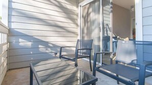 A balcony with a glass door, two chairs, and a table. - Boulevard Stays Quiet 1BR King Suite, Pool Access, Gym (Irving)