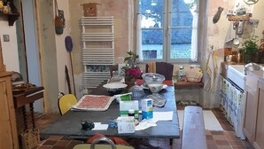 Une cuisine équipée d’une table à manger, de chaises, d’un banc, d’une fenêtre et de divers ustensiles de cuisine.