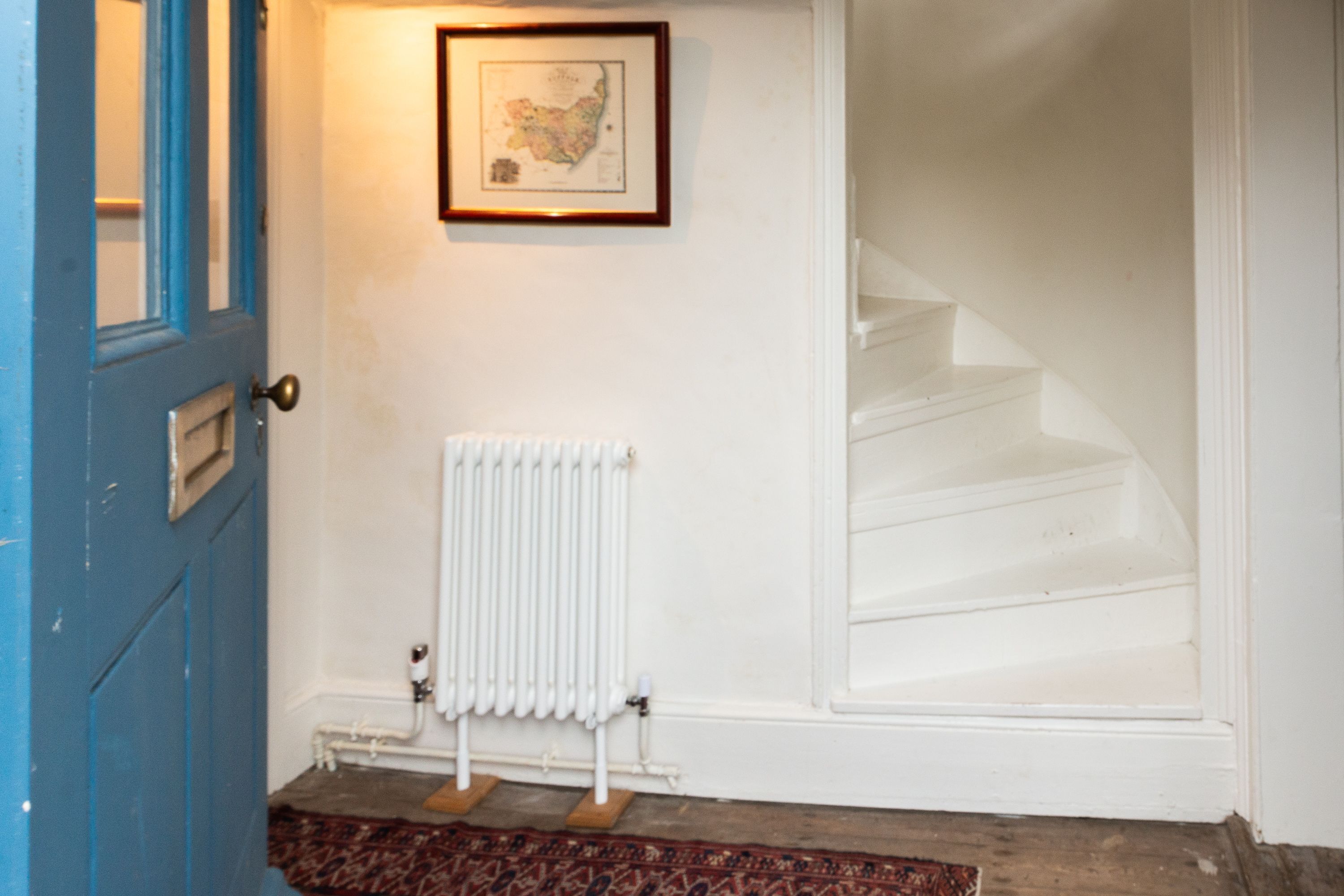 A blue door, a white radiator, and a staircase.