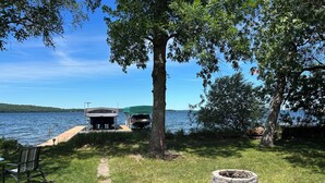 Una terrazza sul lago con una panchina, un braciere e due imbarcazioni ormeggiate al pontile.