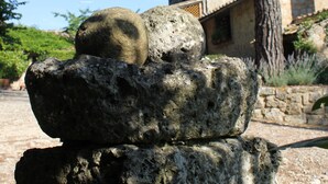 Une pile de pierres de formes irrégulières, avec un arbre et un bâtiment en arrière-plan.