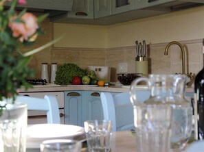 Una cocina con un lavamanos, encimera y diversas frutas y verduras.