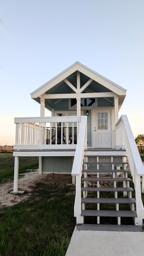 Et strandhus med veranda, trappe og dør.