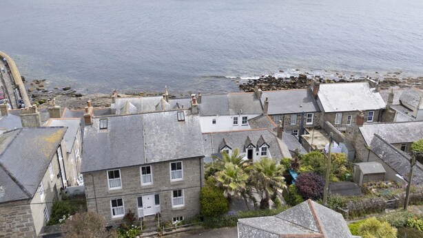 A coastal town with stone buildings, a rocky breakwater, and a view of the sea. - St Clements Cottage - Free WiFi - Outdoor kitchen and shower - Wood Burner (Mousehole)
