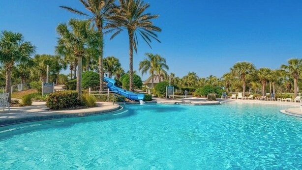 Ein Swimmingpool mit einer blauen Rutsche und Palmen.