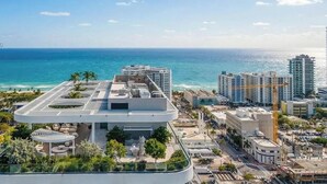 Ein modernes Hotel mit Dachterrasse, umgeben von Stadtgebäuden und Blick auf das Meer.