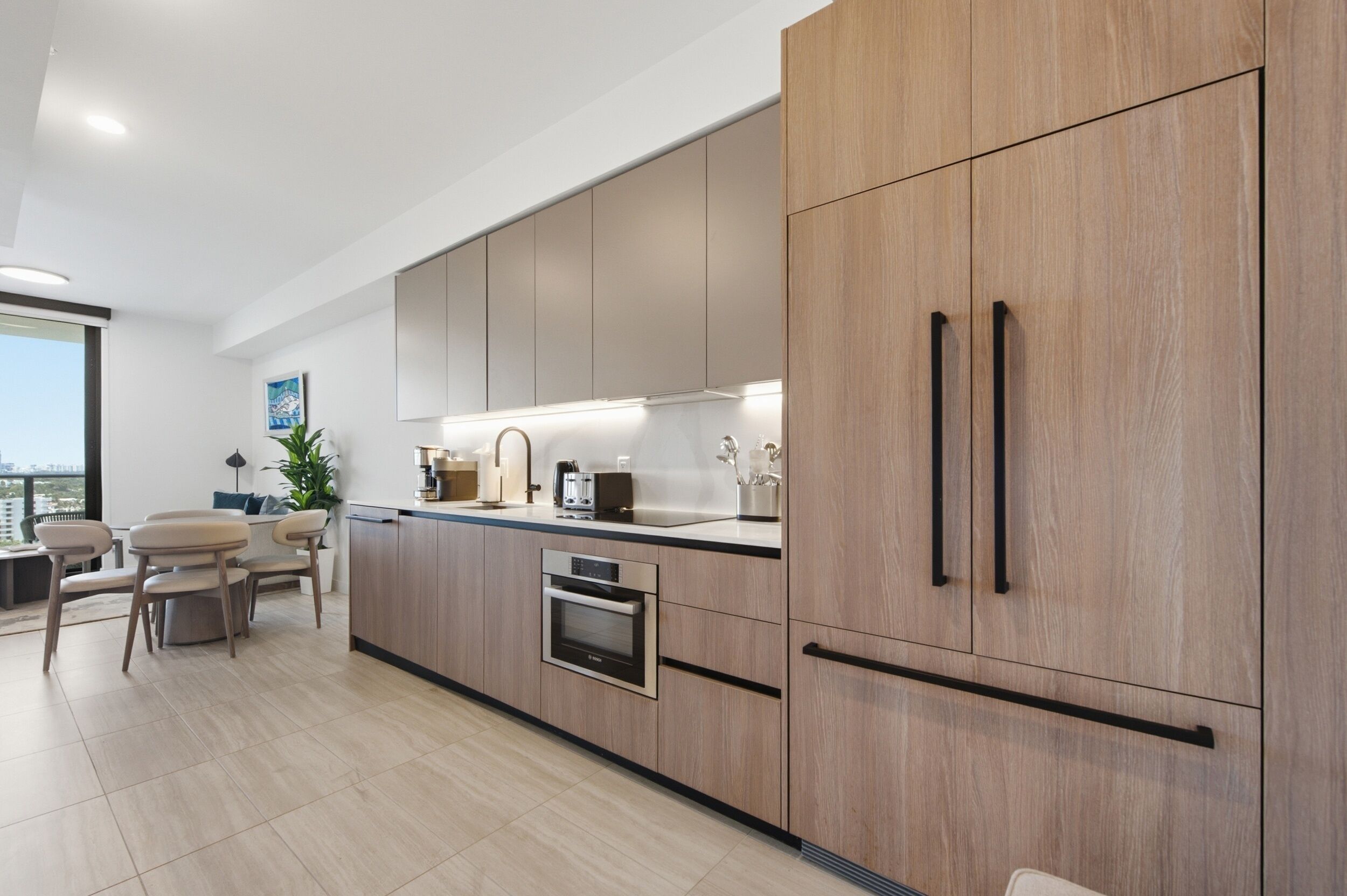Una cocina moderna con armarios de madera, horno empotrado y comedor con vistas.