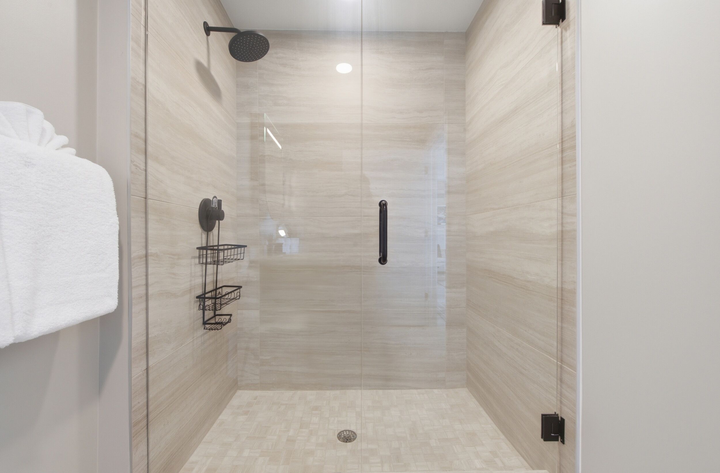 Ducha moderna con puerta de cristal, toallero y cabezal de ducha.