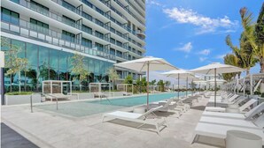 Ein modernes Hotel mit Poolbereich, Liegestühlen und Sonnenschirmen.