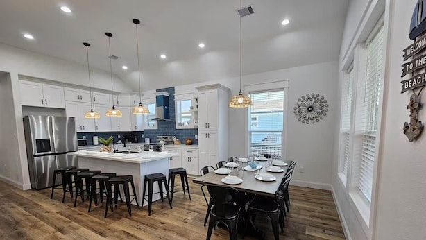 Una cocina moderna con armarios blancos, una isla central e iluminación colgante.