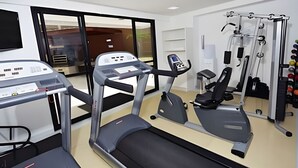 Une salle de sport équipée de machines de cardio, de matériel de musculation et d’un tapis de course.