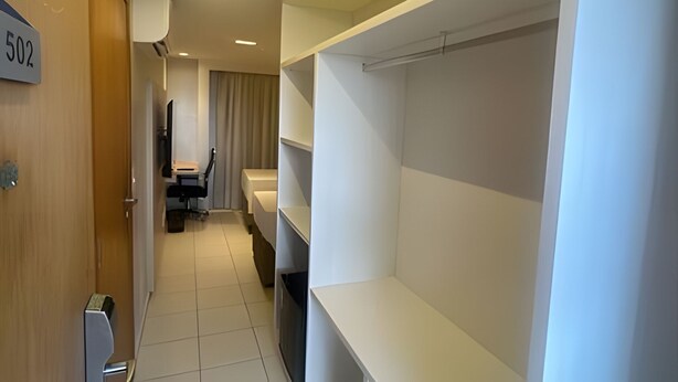 Un couloir d’hôtel avec une porte en bois portant l’inscription « 502 », un bureau avec une chaise et un lit avec une tête de lit.