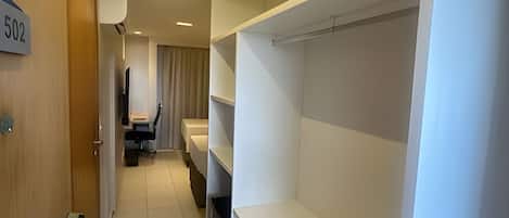 A hotel corridor with a wooden door labeled "502", a desk with a chair, and a bed with a headboard.