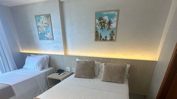 Une chambre d’hôtel avec deux lits, une table de chevet et des œuvres d’art accrochées aux murs.