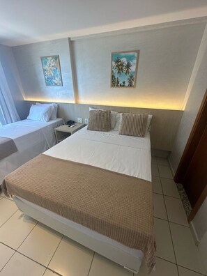 Une chambre d’hôtel avec deux lits, une table de chevet et des œuvres d’art accrochées aux murs.