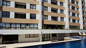 Een modern hotel met een zwembad, meerdere balkons en een strak, eigentijds design.