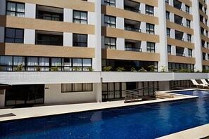 Un hotel moderno con piscina, numerosi balconi e un design pulito e contemporaneo.