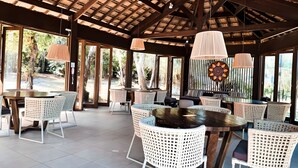 An open-air dining area with wicker furniture, a wooden ceiling, and large windows. - Village with 2 Suites Facing Timeantube Lagoon - Timeantube Reserve, Praia do Forte (Açu da Torre)