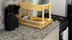 Een keuken met een granieten aanrecht, een geel snijplank, een fornuis en diverse keukengerei.