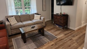 Ein Wohnzimmer mit einer Couch, einem Couchtisch, einem Fernseher und Holzboden.