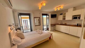 Een slaapkamer met een bed, nachtkastje en uitzicht op het balkon.
