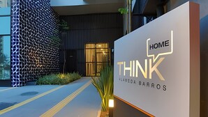 A modern building entrance with a sign reading 'HOME THINK' and 'JULIA BARROS'. - Studio SC (São Paulo)