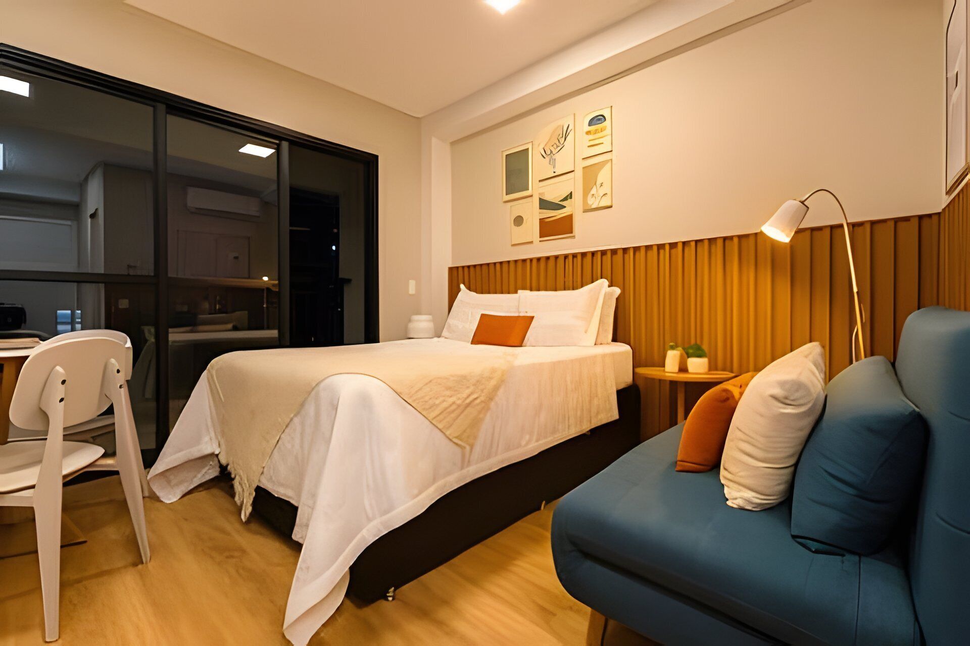 A hotel room with a bed, a desk, a chair, a sofa, and a lamp.