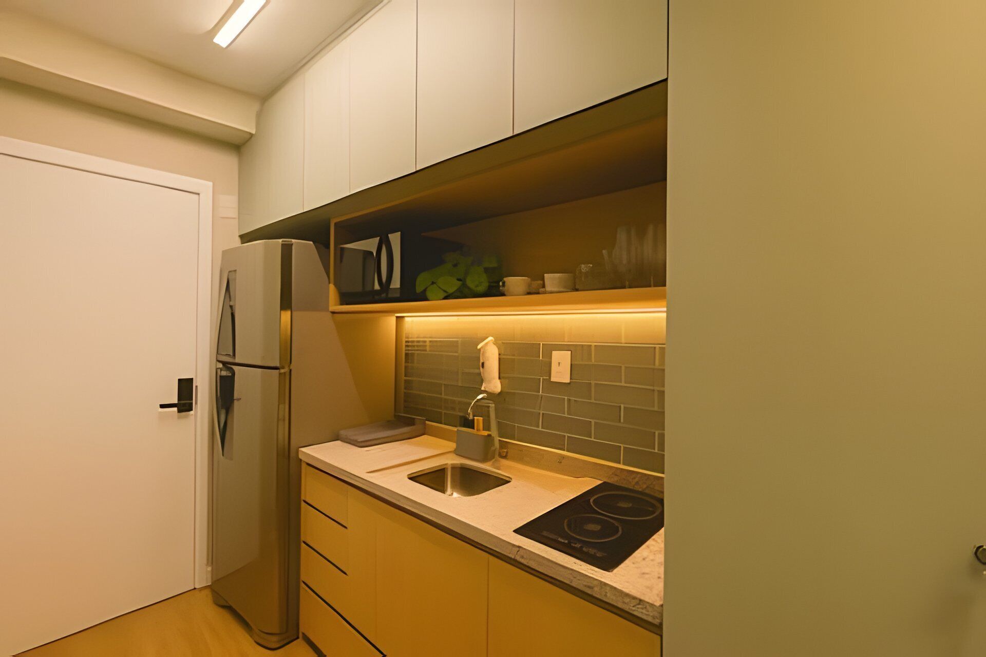 A compact kitchen with a refrigerator, sink, and stove.