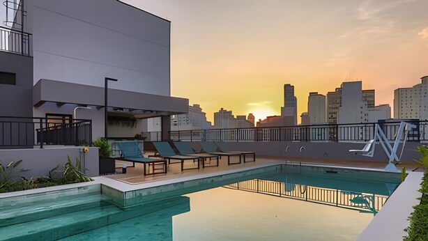 A rooftop pool with lounge chairs, a city skyline view, and a modern building facade. - Studio SC (São Paulo)