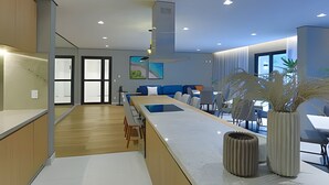 A modern kitchen with a central island, wooden flooring, and a dining area with a blue sofa. - Studio SC (São Paulo)