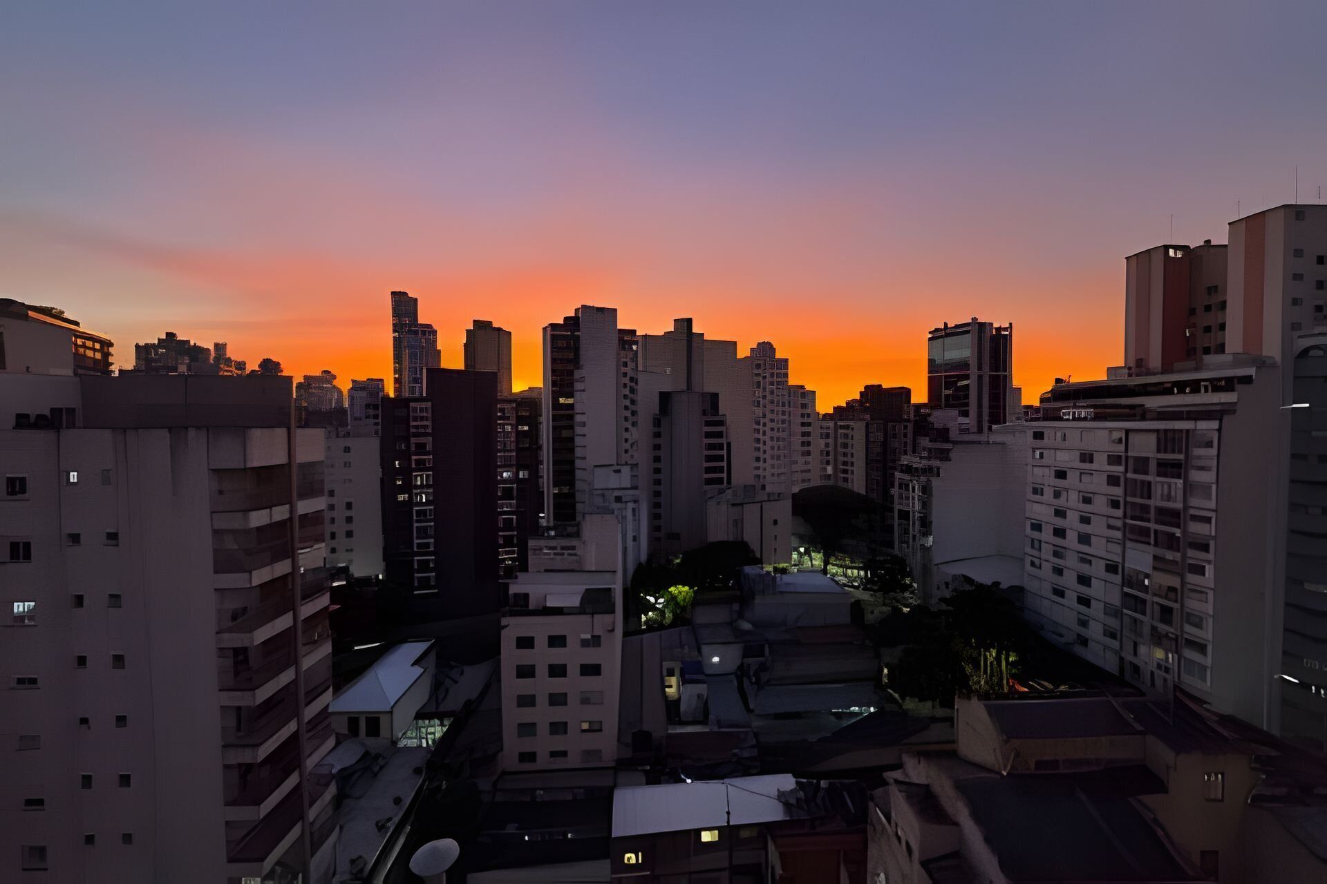 A cityscape at dusk with high-rise buildings and a sunset.