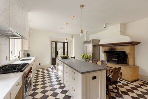 A kitchen with a checkered floor, a central island, a built-in oven, and pendant lighting.