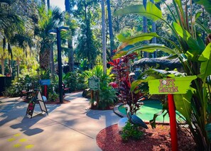 A pathway through a lush garden with signs indicating 'Paradise Falls' and 'Lost Lagoon'.