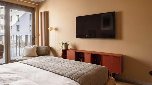 A bedroom with a bed, a window, a wall-mounted TV, and a small cabinet. - LILY APART Żurawie Premium stay (Gdańsk)