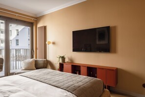 A bedroom with a bed, a window, a wall-mounted TV, and a small cabinet. - LILY APART Żurawie Premium stay (Gdańsk)