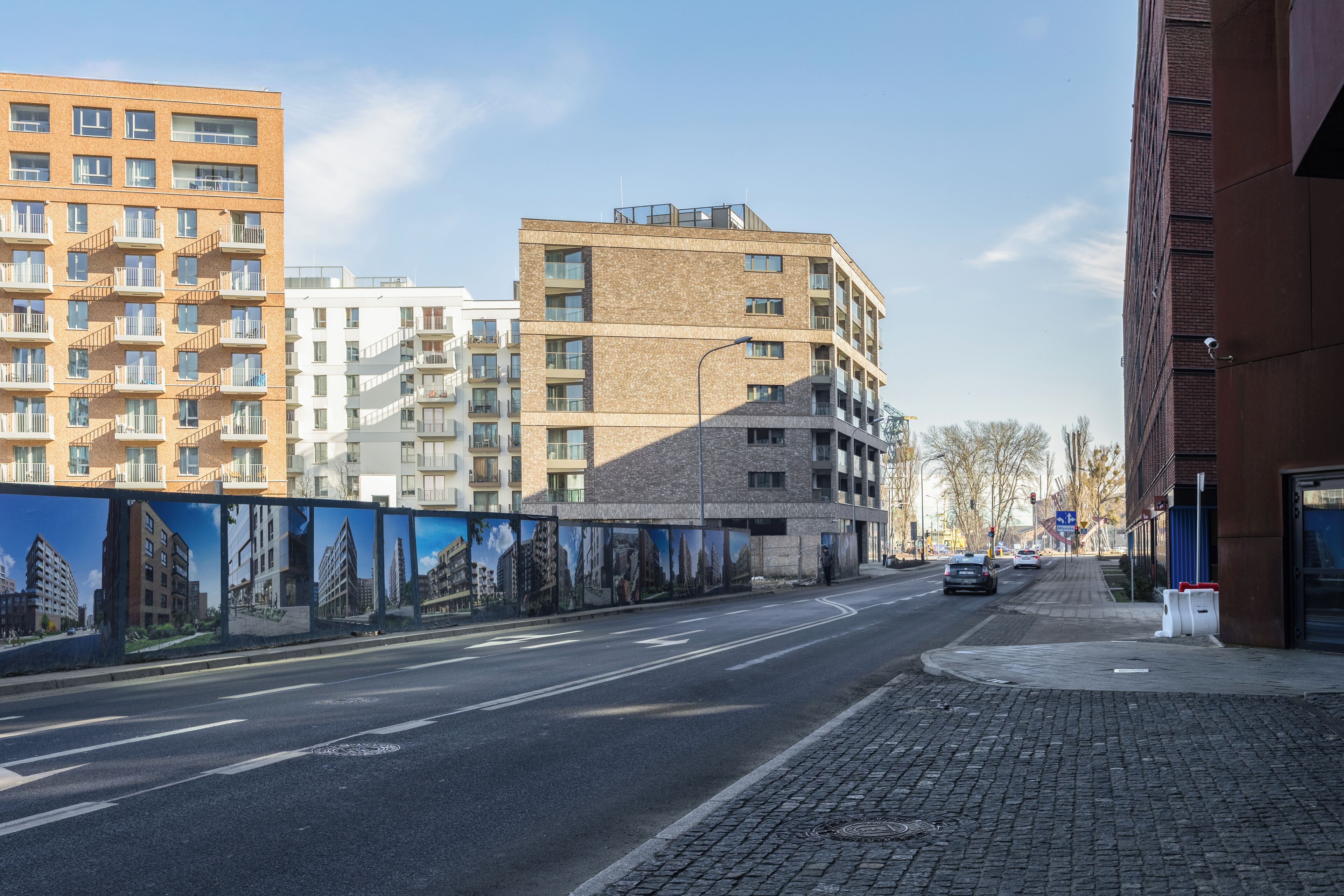 A multi-story building with a brick facade, a pedestrian sidewalk, and a road with vehicles.