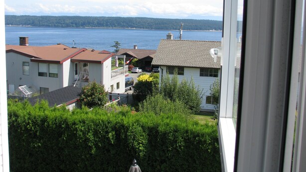 Un quartier résidentiel avec des maisons, un plan d’eau et une chaîne de montagnes à l’horizon.