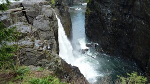 Une cascade se déversant dans un ravin rocheux, entourée d’une végétation luxuriante.