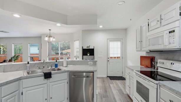 A modern kitchen with white cabinetry, a stainless steel dishwasher, a built-in oven, and a microwave. - Private Pool & Patio & Poker & Kids Play Room (San Antonio)