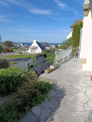 Ein steiniger Weg führt zu einem weißen Gebäude mit Blick auf das Meer.