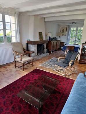 Ein Wohnzimmer mit Kamin, Esstisch und blauem Sofa.