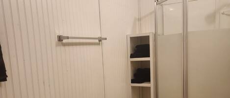 Een badkamer met een toilet, een douchecabine en een plankkast.