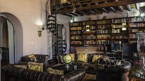 A library with leather sofas, a globe, and bookshelves filled with books. - Casa Estrella (Cartagena)