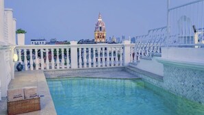 A rooftop pool with a white balustrade, a decorative building in the background, and a clear sky. - Casa Estrella (Cartagena)