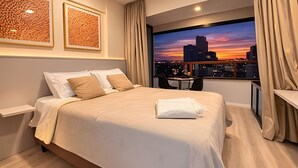A hotel room with a bed, a desk, a chair, and a large window with a cityscape view. - Bela Cintra (São Paulo)
