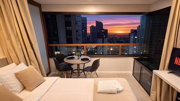 A hotel room with a bed, a small table with chairs, a TV, and a large window with a city view. - Bela Cintra (São Paulo)
