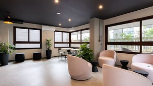 A modern office space with large windows, seating areas, and potted plants. - Bela Cintra (São Paulo)