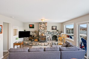 A living room with a stone fireplace, a gray sofa, and a television.